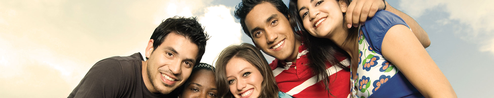 A group of smiling people hold each other and look into the camera.
